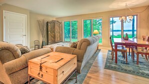 A cozy living room with a sofa, a wooden chest, and a dining table with chairs. - Interlochen Home on Green Lake w/ Dock & Beach! (Interlochen)