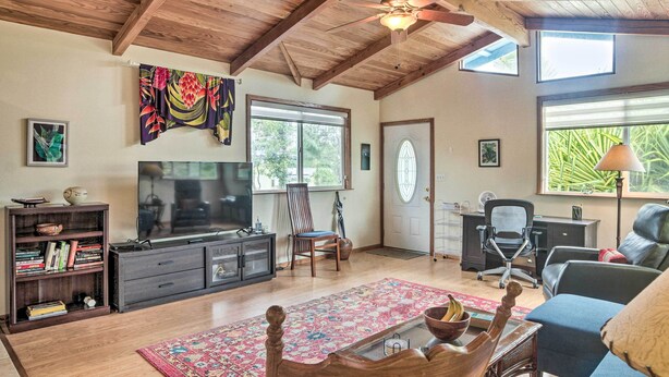 A spacious living room with a large TV, wooden ceiling, and a view of greenery outside. - P'hoa Home 4 Mi to Kilauea Caverns of Fire! (Pahoa)