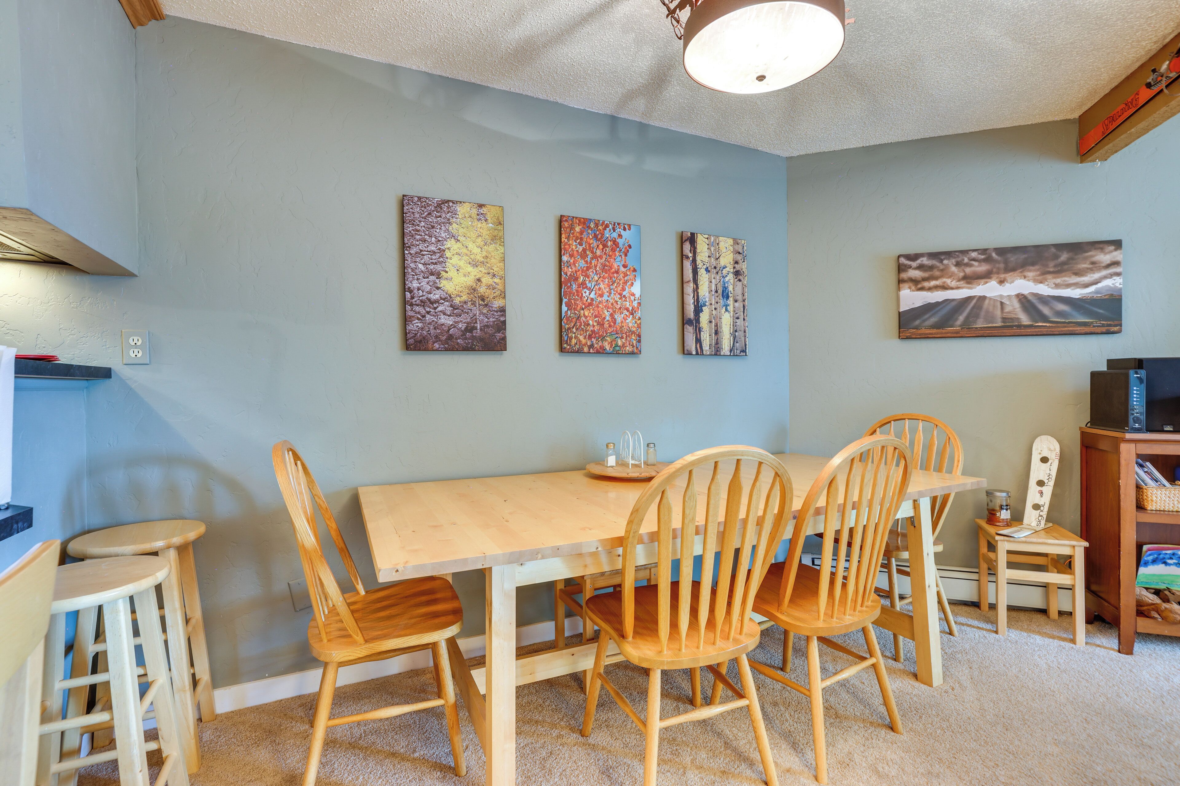 A dining area with a wooden table and chairs, a television, and artwork on the wall.
