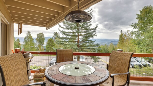 A balcony with wicker chairs, a glass-top table, and a hanging light fixture. - Silverthorne Condo w/ Lake Views: 10 Mi to Skiing! (Silverthorne)