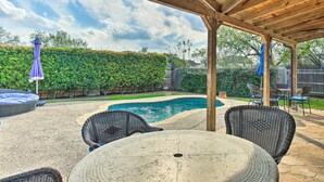 A covered patio area with a pool, wicker furniture, and a sign reading "life to better by the pool."