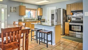 A kitchen with a central island, wooden cabinets, stainless steel appliances, and a dining area with a table and chairs.