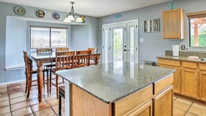 A kitchen with a granite island, wooden cabinets, and a dining area with a table and chairs.