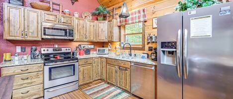 A kitchen with wooden cabinets, stainless steel appliances, and a wooden floor.