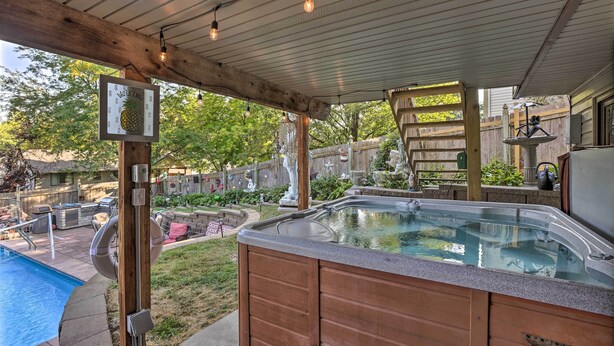 Un patio trasero con jacuzzi, piscina y un pérgola de madera.