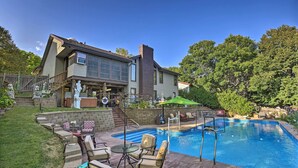 Una casa con piscina, zona de estar exterior y una escalera de piedra que lleva a la entrada.