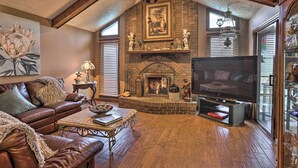 Una sala de estar acogedora con chimenea, sofá de cuero y televisor de pantalla plana.