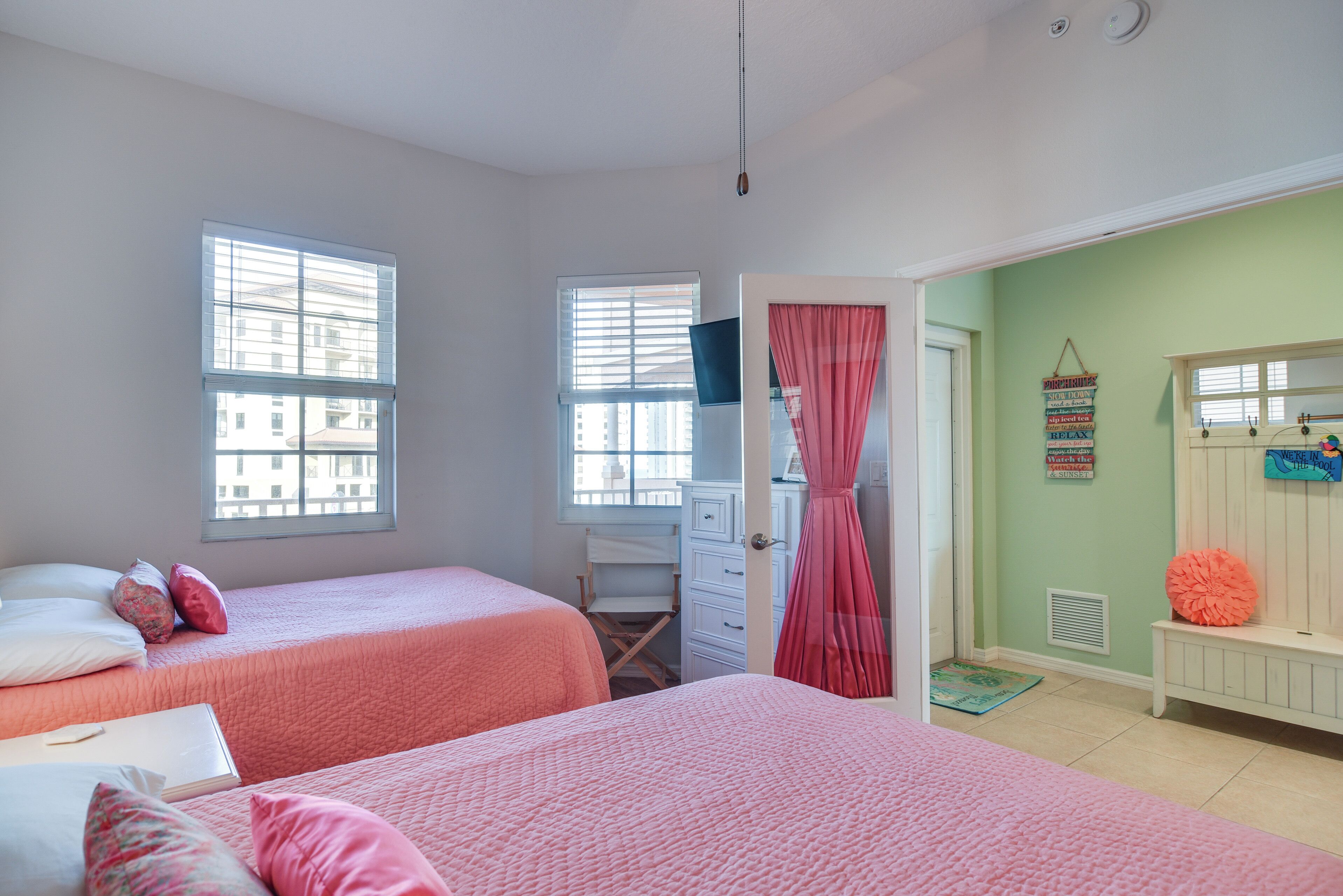 A bedroom with two beds, a desk, and a window.