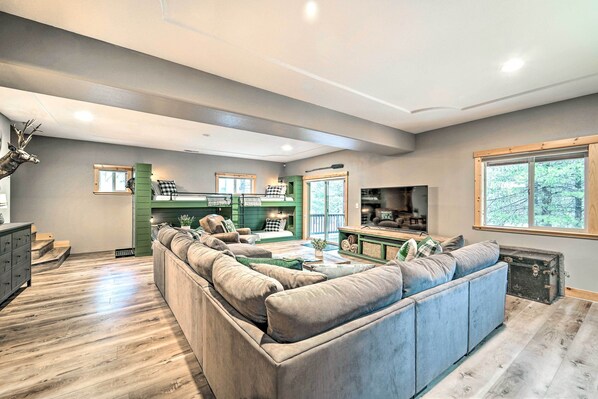 A spacious living room with a large sectional sofa, a dining area, and a kitchen. - Bikes, Grill & Views: Luxe Truckee Cabin! (Truckee)