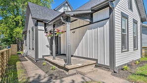 Ein Wohnhaus mit überdachter Veranda, Garage und Vorgarten mit Holzzaun und kleinem Garten.