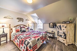 A bedroom with a large bed, a wooden dresser, a nightstand, and a window with a view of the outdoors. - 1 Block to Downtown: Cozy Condo by Mirror Lake (Lake Placid)