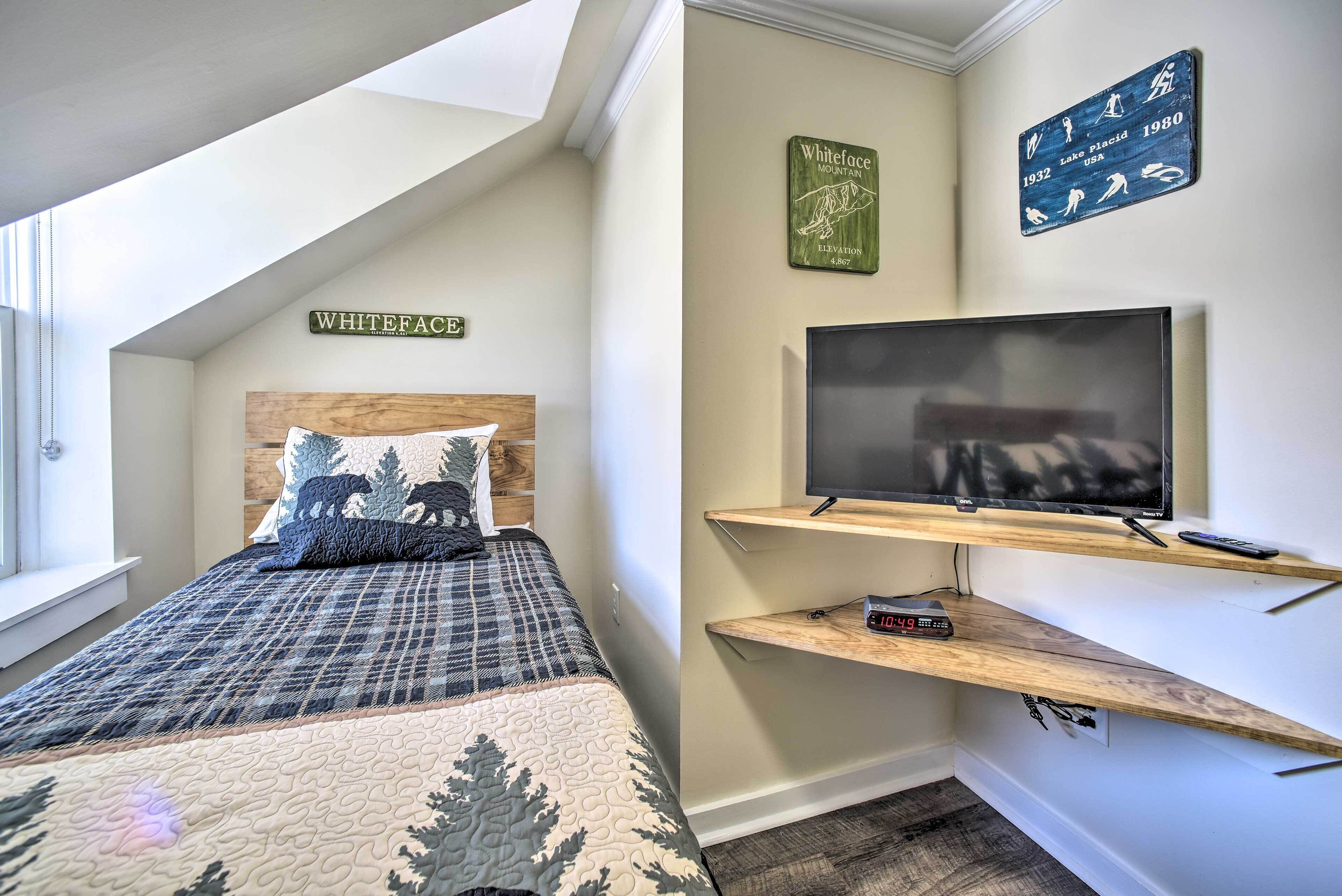 A bedroom with a bed, a TV, and a mounted shelf.