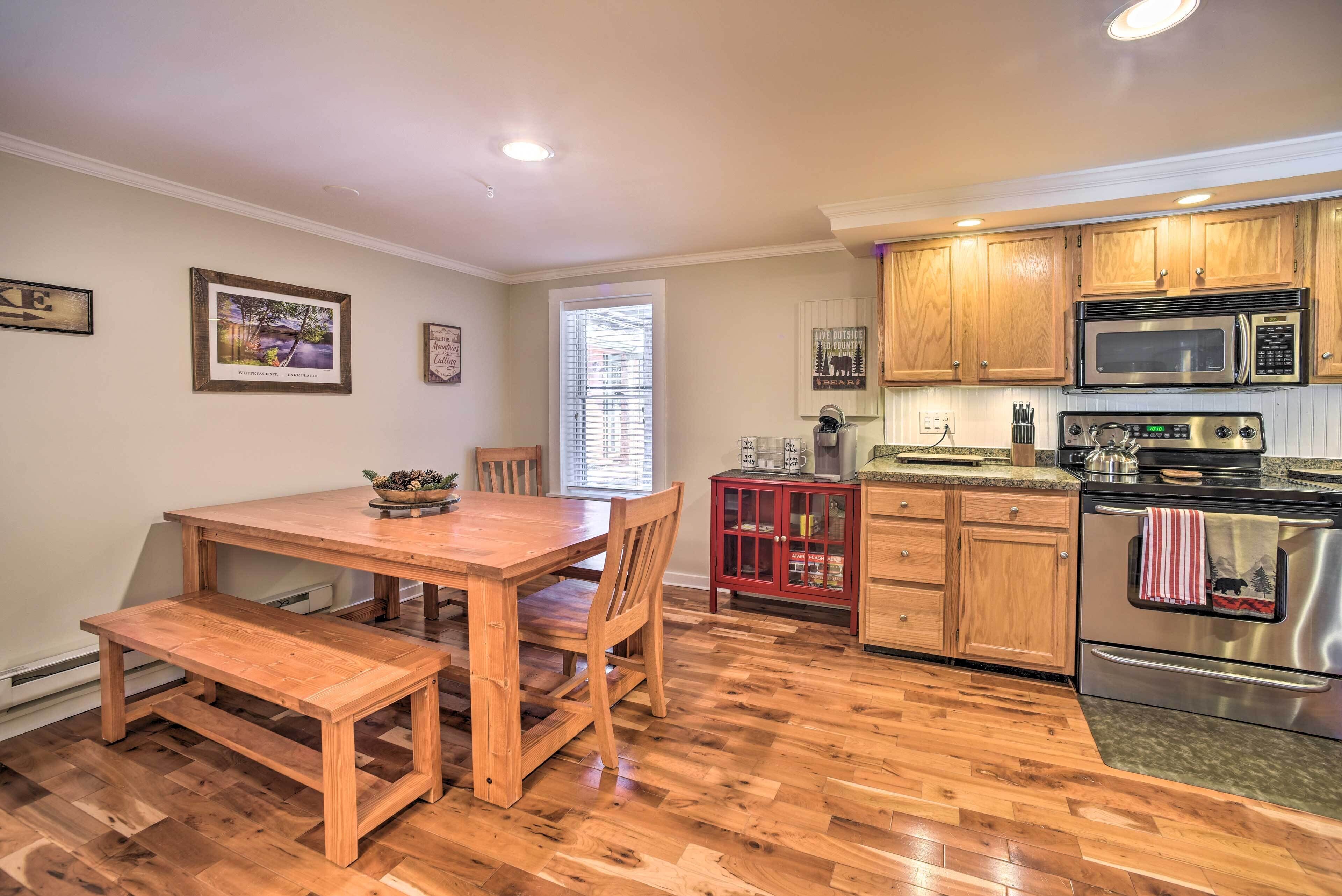 A kitchen with wooden cabinets, a stainless steel stove, and a dining table with benches.