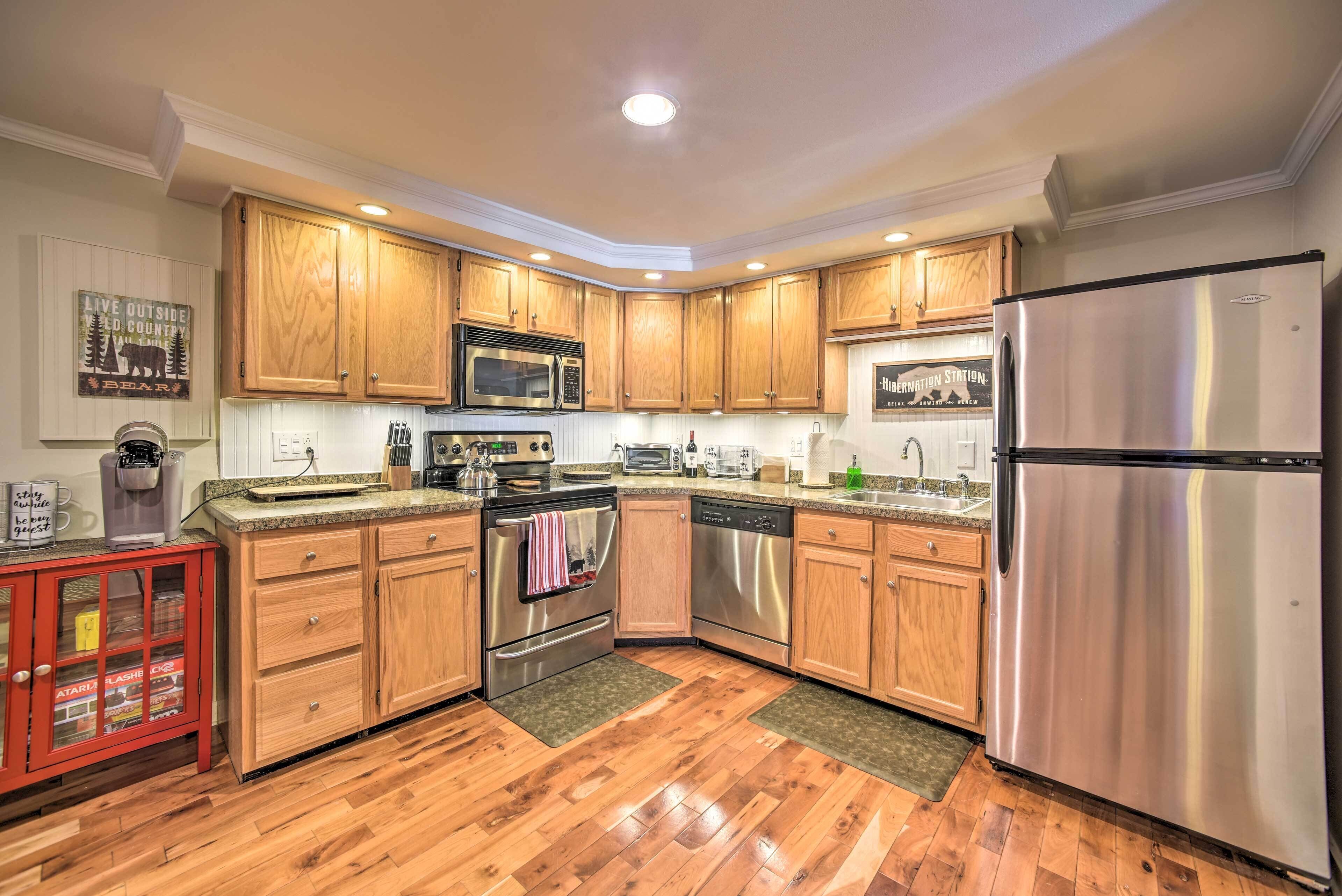 A modern kitchen with wooden cabinets, stainless steel appliances, and a red cabinet with glass doors.