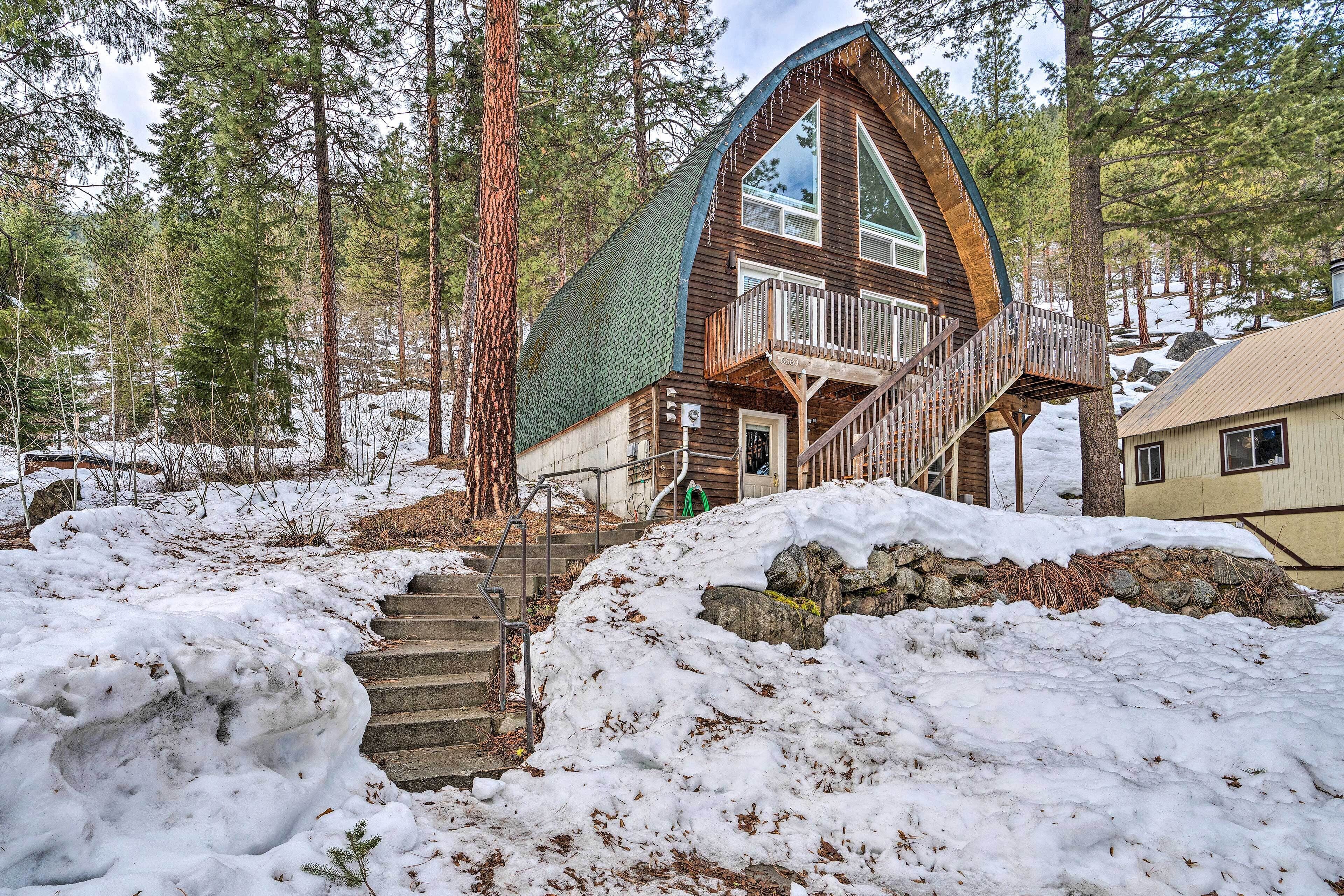 A cabin with a wooden exterior, a balcony, and a staircase leading to the entrance.