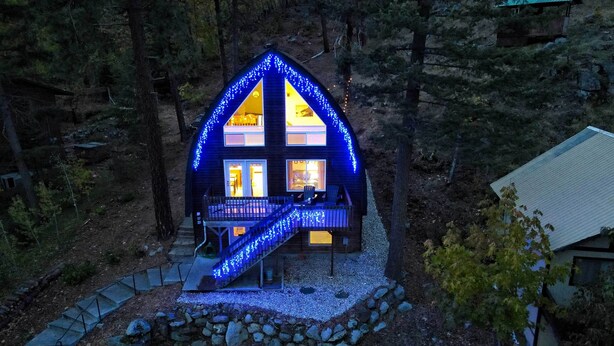 A cabin with a steeply pitched roof, a covered deck, and a staircase leading to the entrance. - Leavenworth Vacation Rental Near Downtown! (Leavenworth)