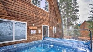 A wooden cabin with a hot tub and a sign indicating a 2 PM closing time. - Leavenworth Vacation Rental Near Downtown! (Leavenworth)