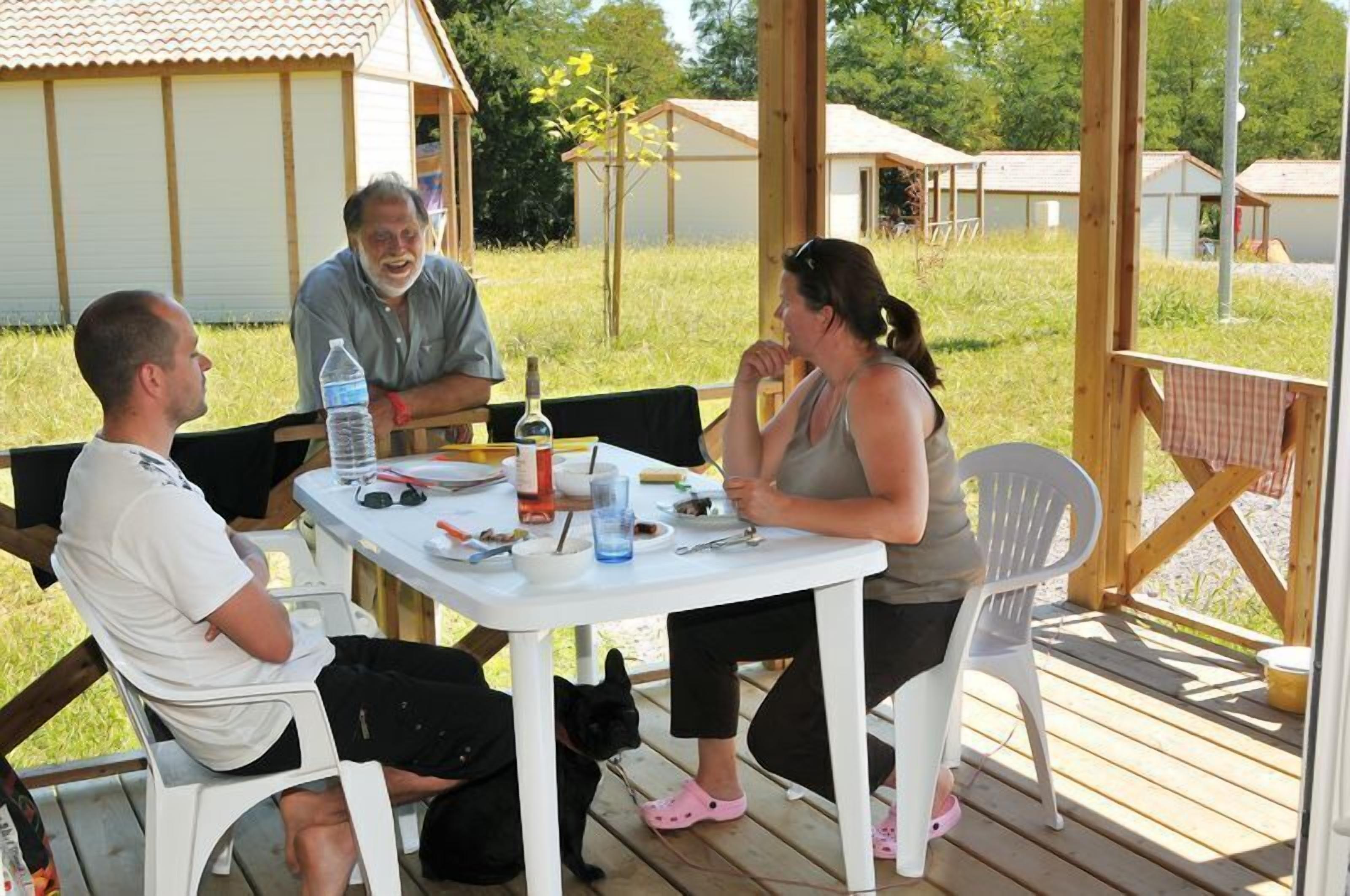 Un grupo de personas sentadas en una mesa con una botella, vasos y comida.