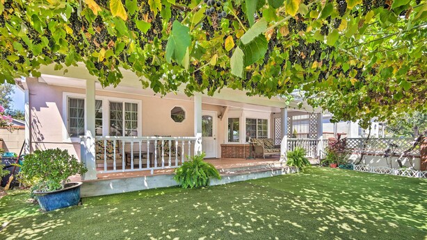 A covered patio area with artificial grass, a white railing, and a potted plant. - Romantic Pasadena Home w/ Covered Porch! (Pasadena)