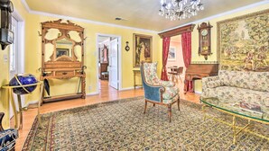 A room with a large ornate mirror, a globe on a stand, a floral armchair, a sofa, and a chandelier. - Romantic Pasadena Home w/ Covered Porch! (Pasadena)