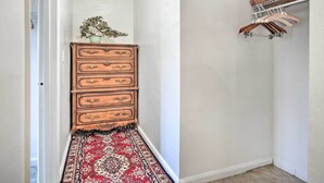 A hallway with a wooden dresser, a red patterned rug, and a clothing rack with hanging items. - Romantic Pasadena Home w/ Covered Porch! (Pasadena)