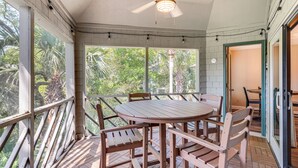 A covered outdoor patio with a wooden table and chairs, surrounded by a white brick wall and a wooden railing. - Blissful Kiawah Island Escape: Walk to the Beach! (Kiawah Island)