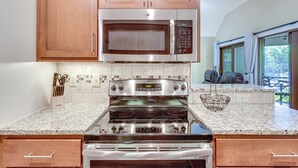 A kitchen with wooden cabinets, a stainless steel microwave, a double oven, and a granite countertop. - Blissful Kiawah Island Escape: Walk to the Beach! (Kiawah Island)