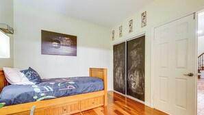 Un dormitorio con una cama de madera, un armario grande y un cuadro en la pared.