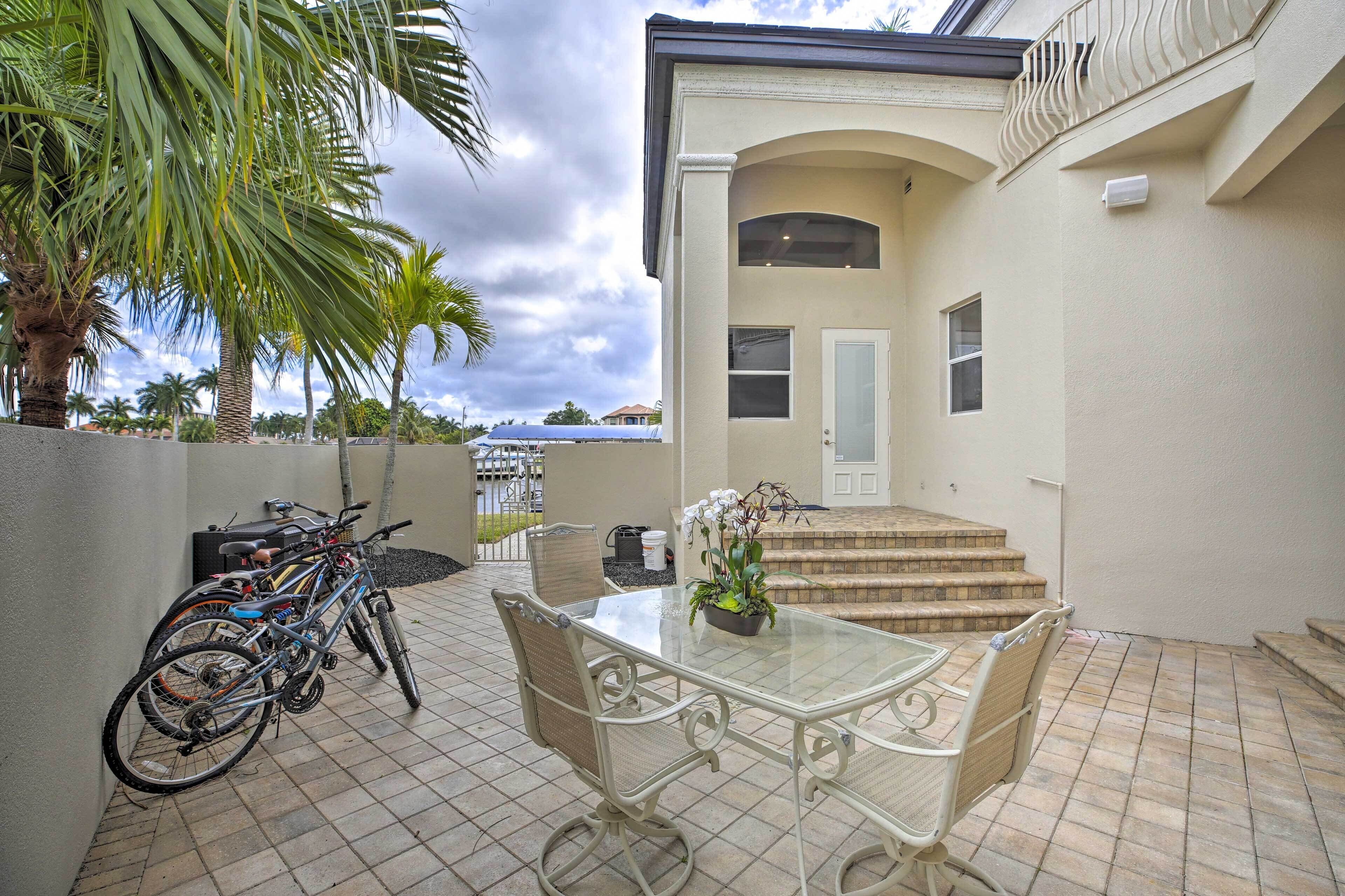 A patio with a glass table and chairs, a bicycle rack, and a staircase leading to a door.