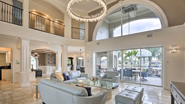 A spacious living area with a high ceiling, a glass coffee table, and a large sofa. - Luxe Cape Coral Escape w/ Boat Dock + Cabana! (Cape Coral)