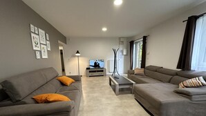 Un salon moderne avec deux canapés gris, une table basse et un téléviseur.