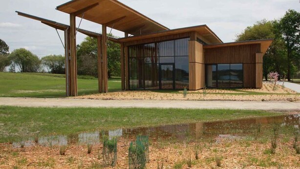 Un bâtiment moderne doté de grandes fenêtres en verre et d’une façade en bois.