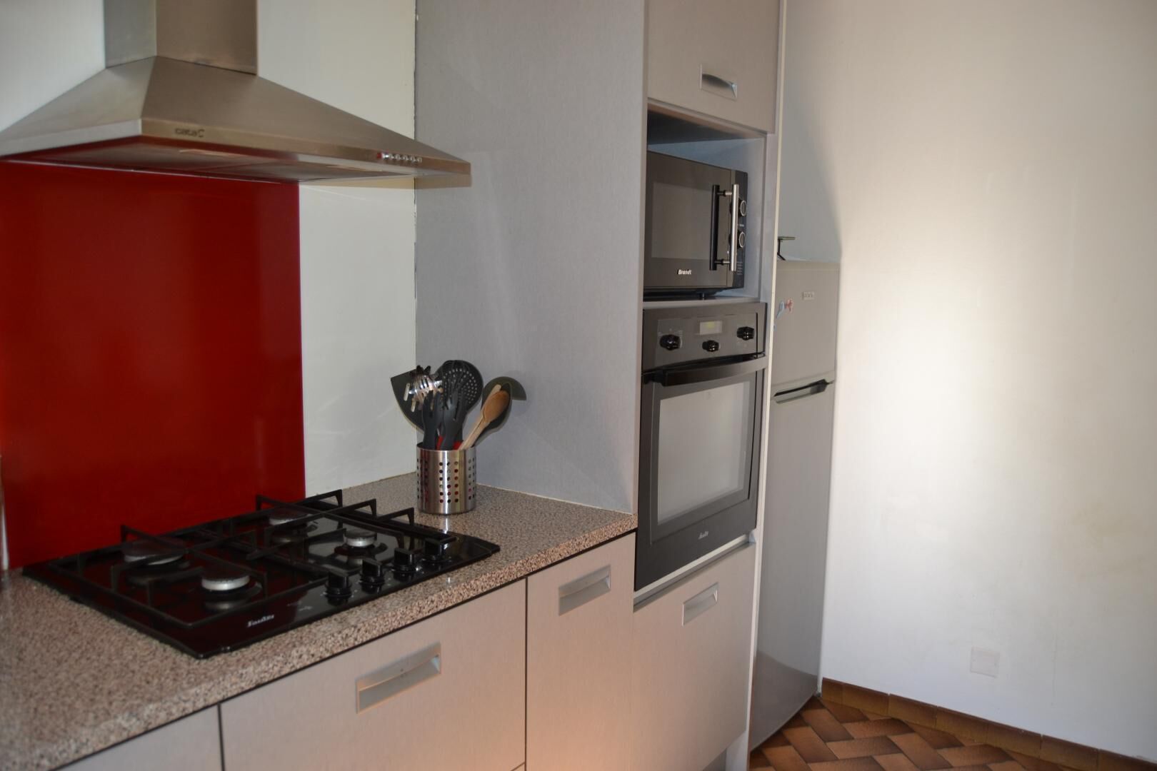 A compact kitchen with a gas stove, a microwave, and a built-in oven.