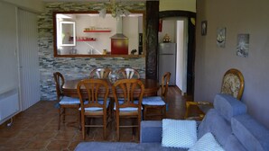 Comedor con pared de piedra, mesa de madera y sillas.