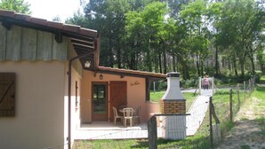 A rustic building with a wooden door and a chimney, surrounded by a fenced garden area. - Lou Parc - Leon - Gîte (LEON)
