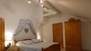 Ein Schlafzimmer mit einem hölzernen Bett, einem Nachttisch, einer Nachttischlampe, einem Kleiderschrank und einem dekorativen Herz auf der Kleider schranktür.
