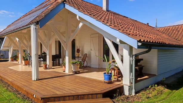 Ein überdachter Patio-Bereich mit Holzboden und Topfpflanzen.