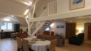 Ein geräumiger Essbereich mit hoher Decke und einer Treppe, die zu einer oberen Ebene führt.