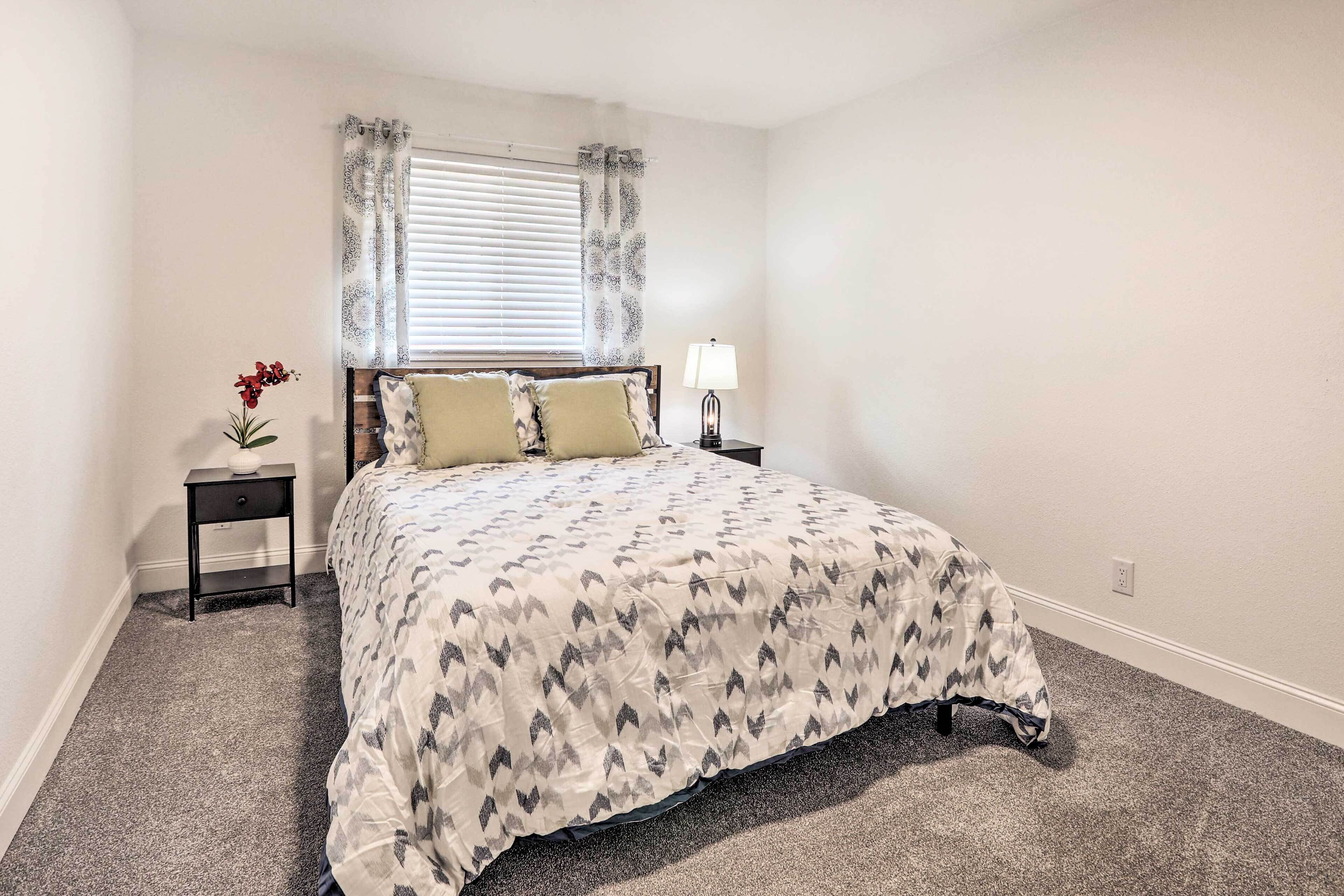 A bedroom with a bed, a nightstand, a lamp, and a window with curtains.