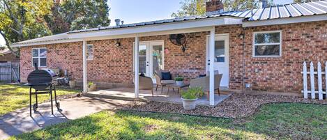 A brick house with a covered patio, a grill, and outdoor seating.