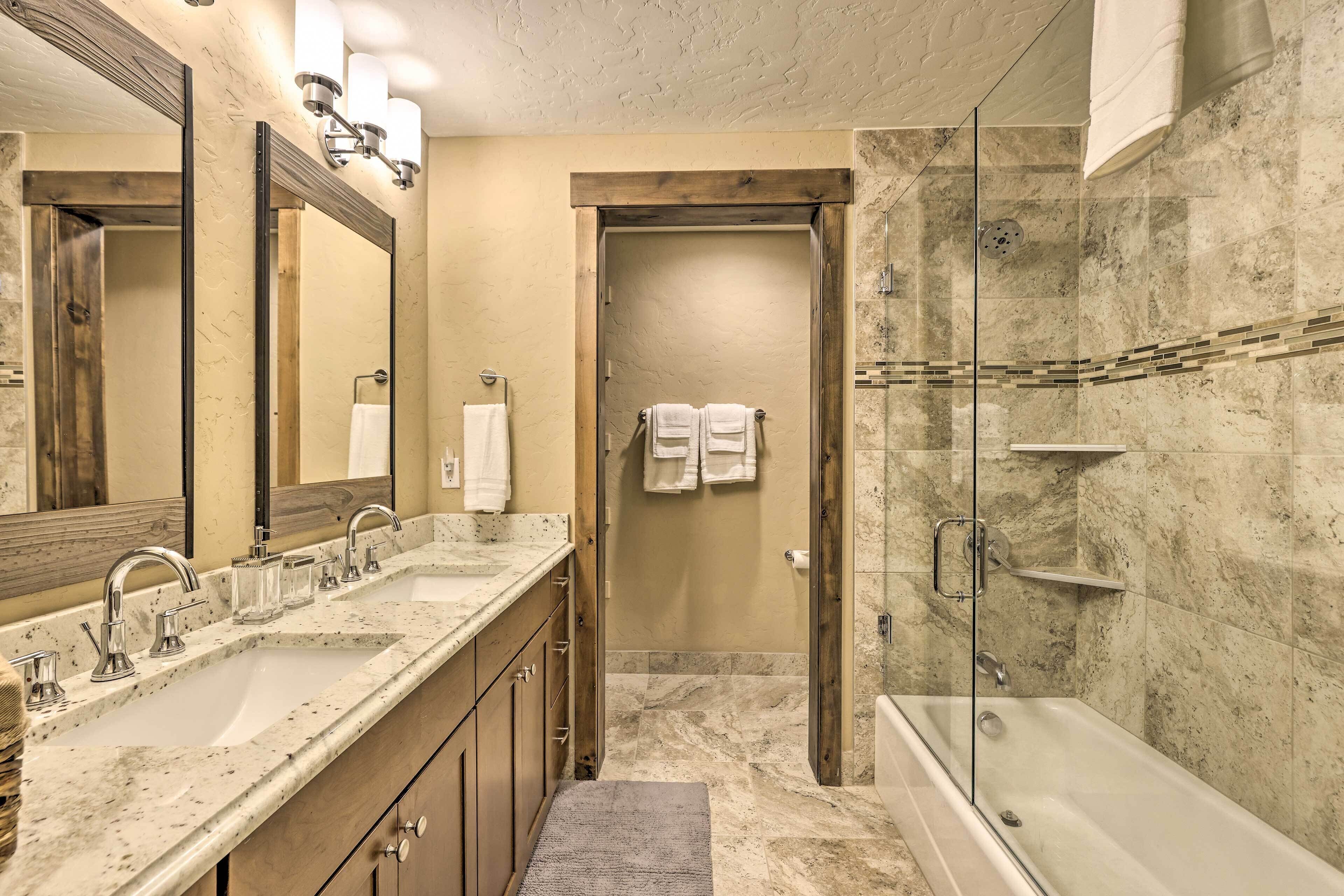 Un baño moderno con lavamanos doble, ducha con mampara de vidrio y un espejo grande.