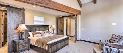 A bedroom with a large bed, bedside tables, a chair, and a desk.