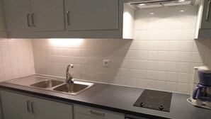 Una cocina con armarios blancos, un lavamanos doble, una estufa integrada y una cafetera.