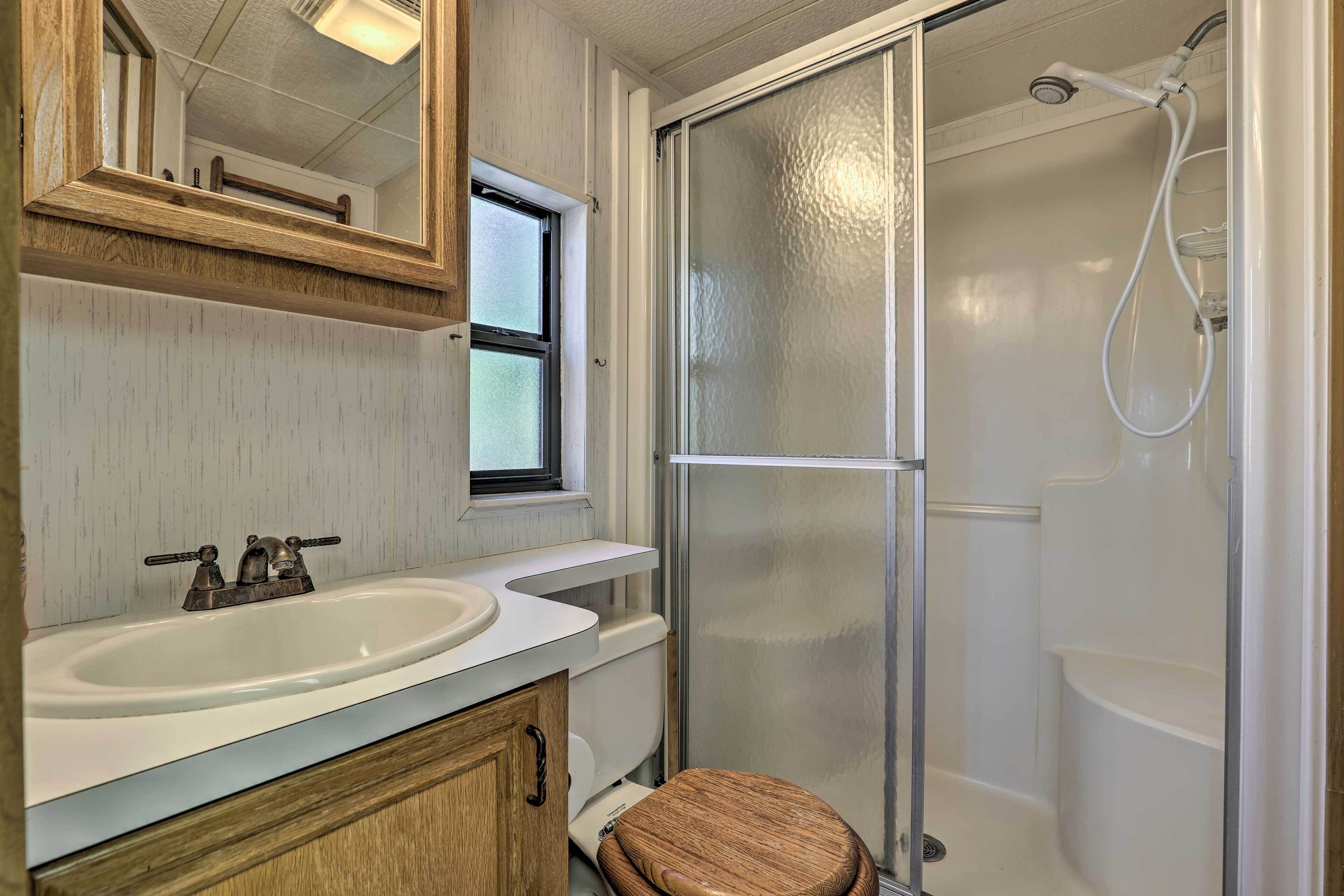 Un baño con lavabo blanco, mueble de madera y cabina de ducha de vidrio.