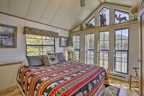 A bedroom with a large bed, multiple windows, and a view of the outdoors.