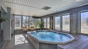 A hot tub in a covered outdoor area with wooden flooring, stone walls, and large windows offering a view of the outdoors. - 6 Mi to Slopes! Mtn-view Breck Gem w/ Resort Perks (Breckenridge)