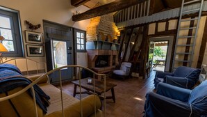 A cozy room with a brick fireplace, a bed with a headboard, and two blue armchairs.