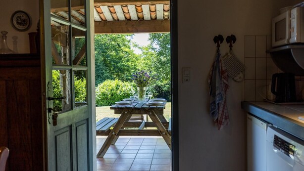 A kitchen with a microwave, a coffee maker, and a wooden table set for dining.