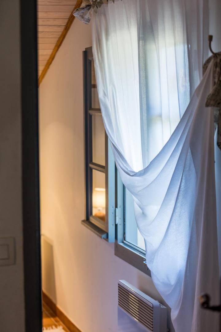 Una habitación con ventana, radiador y cortina.