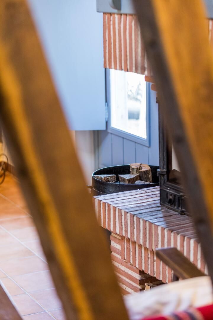 A room with a brick fireplace, a window, and a view of the outside.
